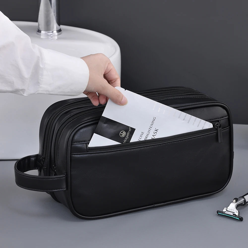 A hand places a white paper inside a black premium PU leather toiletry bag.