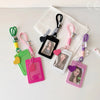 A collection of pink, green, and purple PU credit card and ID holder keychains displayed on a white cloth.