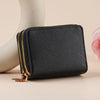 Black leather heart-shaped zipper wallet with gold stitching resting on a light surface.