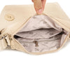 A hand is opening a beige waterproof nylon crossbody bag, showing the interior lining and zipper.