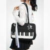 A woman is holding a black and white piano print crossbody bag with a white knit sweater and a black polka dot skirt.