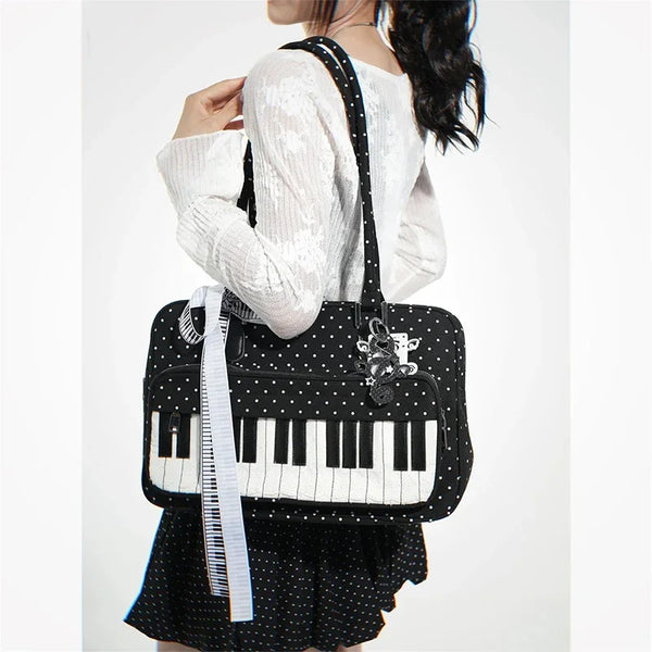 A woman is holding a black and white piano print crossbody bag with a white knit sweater and a black polka dot skirt.