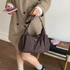 A person is holding a plaid nylon drawstring tote bag in front of a beige coat.