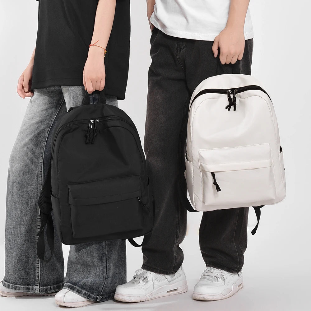 A person is holding a white leisure shoulder backpack and black pants.