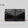 Black alligator pattern leather clutch bag with gold chain detail.