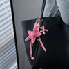 Sac à main noir avec un porte-clés en forme de ballon d'étoile et de fleur rose suspendu à la sangle.