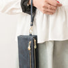 A dark blue retro long wallet with a double zipper is held by a person wearing a white blouse.