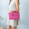 A woman is holding a pink portable Oxford cloth toiletry bag against a light blue background.