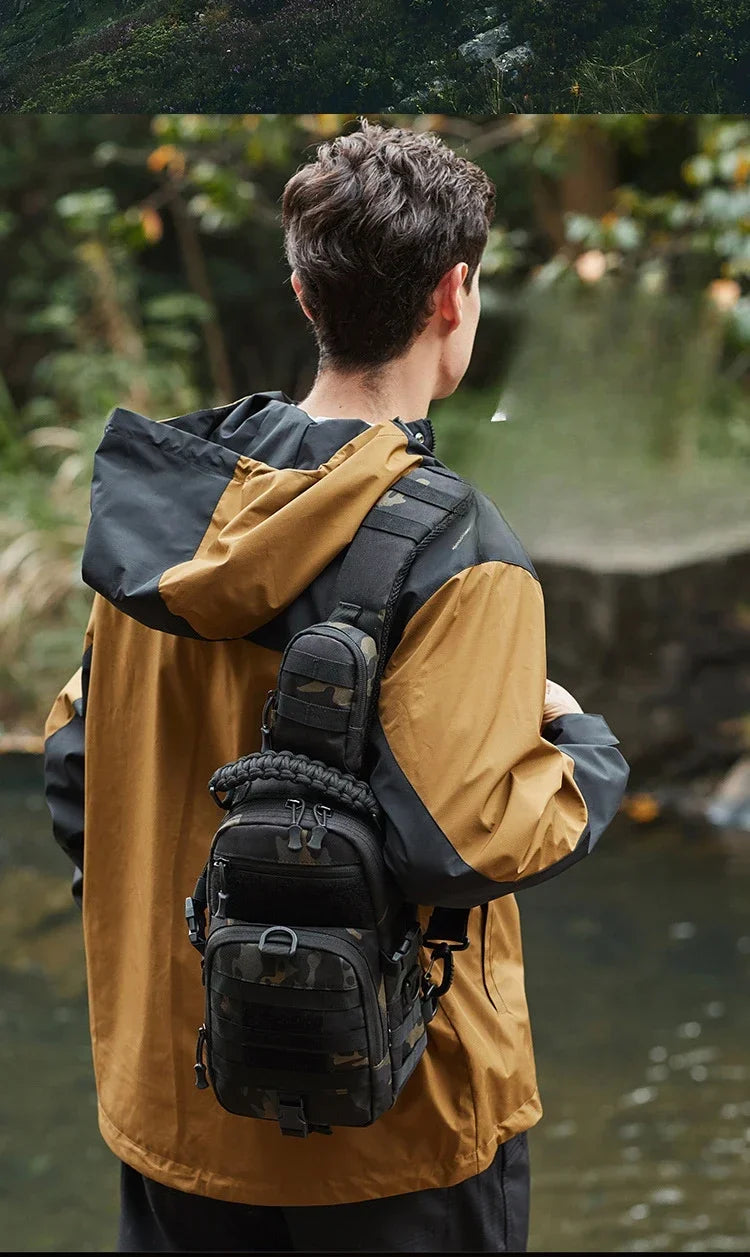 A person wearing a tan jacket and black pants is carrying a tactical chest bag in an outdoor setting.