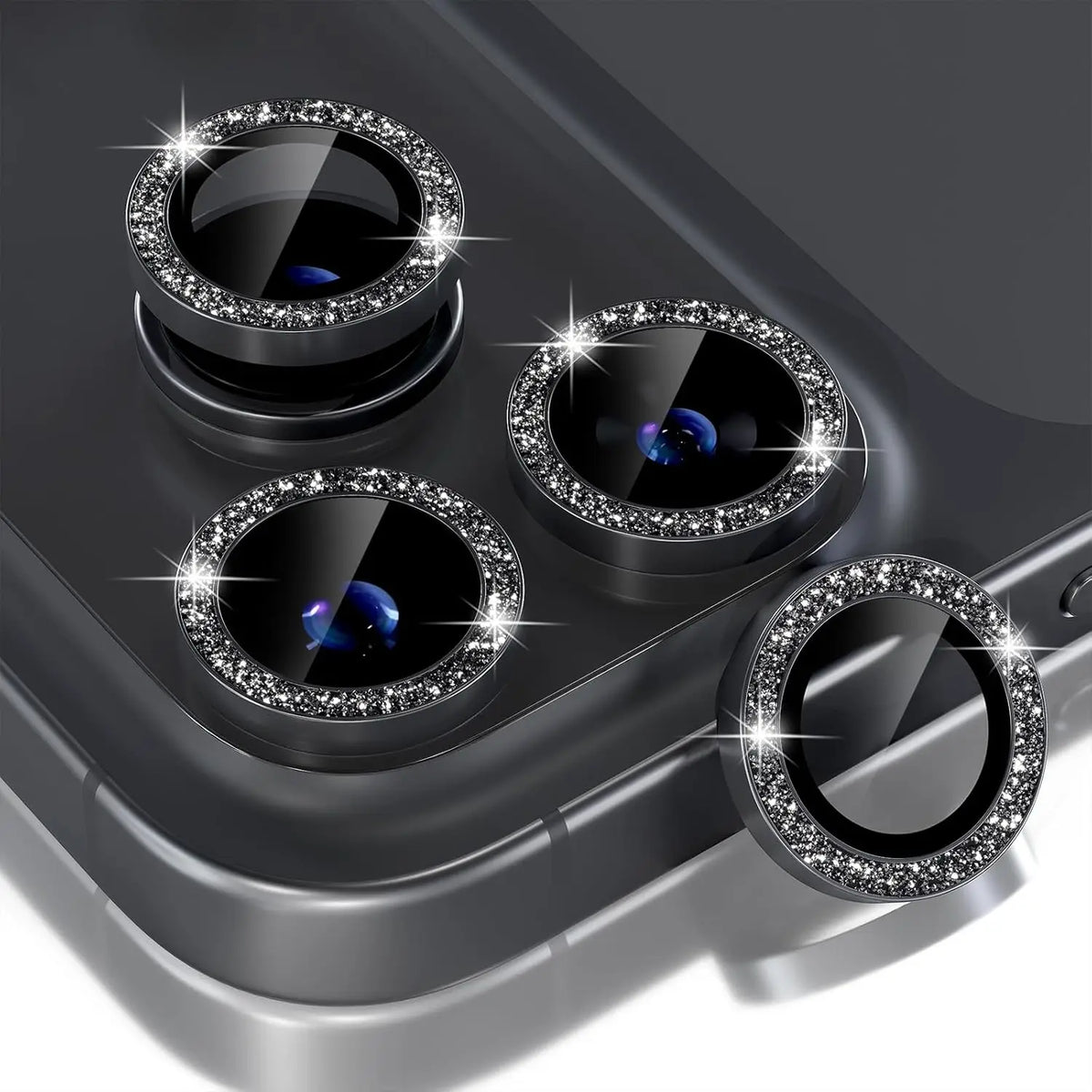 A close-up view of a silver glitter diamond camera lens protector with a metal frame for an iPhone.