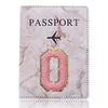 Portafolios de cuero texturizado rosa y dorado con la palabra PASAPORTE e ícono de avión estilizado.