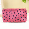 A pink cosmetic bag with a leopard print pattern and a zipper, lying on a white surface.