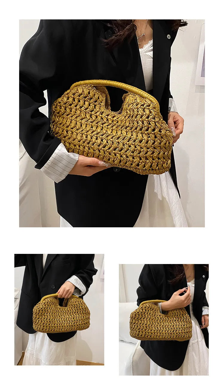 A woman holds a woven straw tote handbag with a natural golden color against a black outfit.