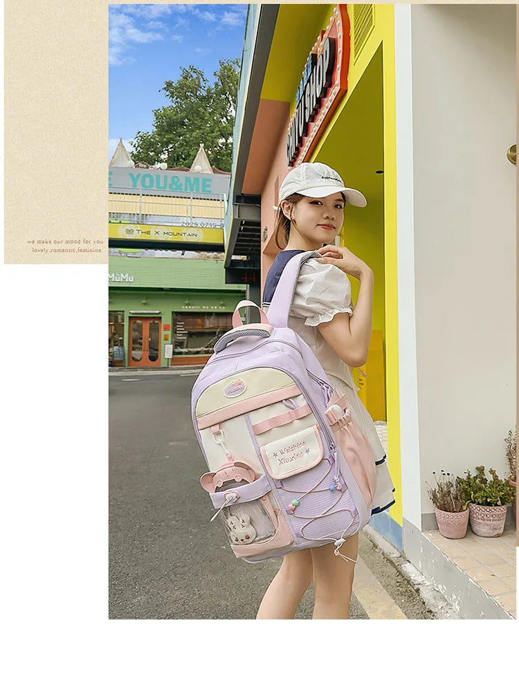 A young woman wearing a light pink Candy Color Campus backpack standing in front of a yellow storefront.