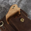 A close-up of a brown genuine leather men's waist bag featuring stitching and brass hardware.