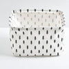 A white storage basket with black and gray pine tree patterns, featuring handles.