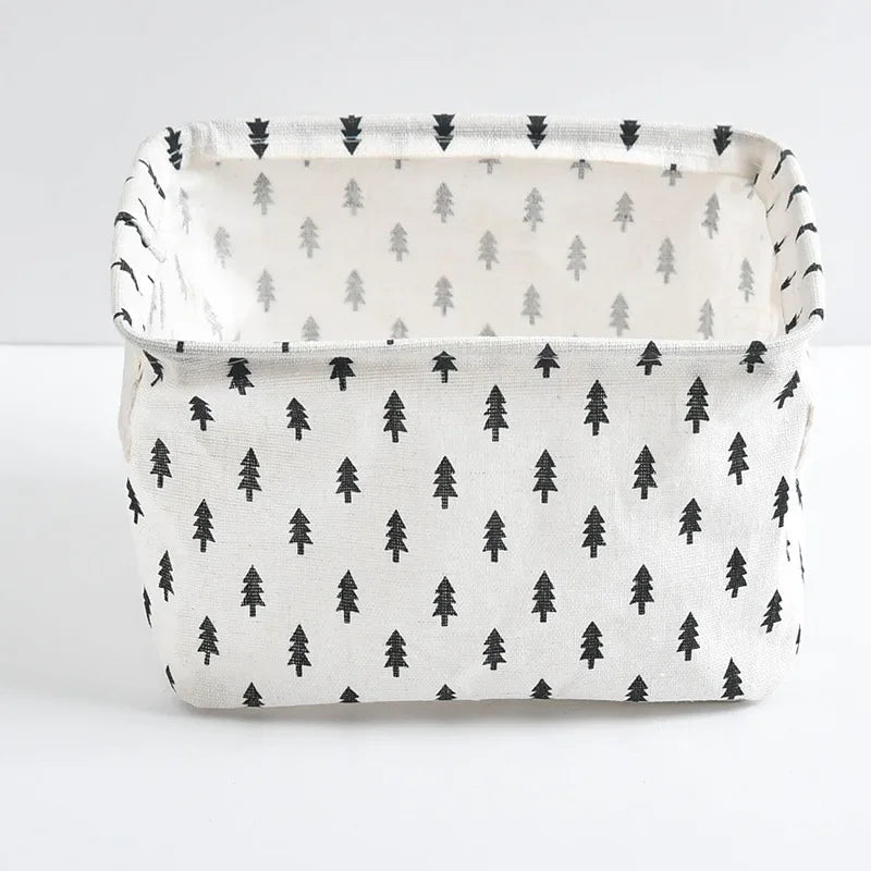 A white storage basket with black and gray pine tree patterns, featuring handles.