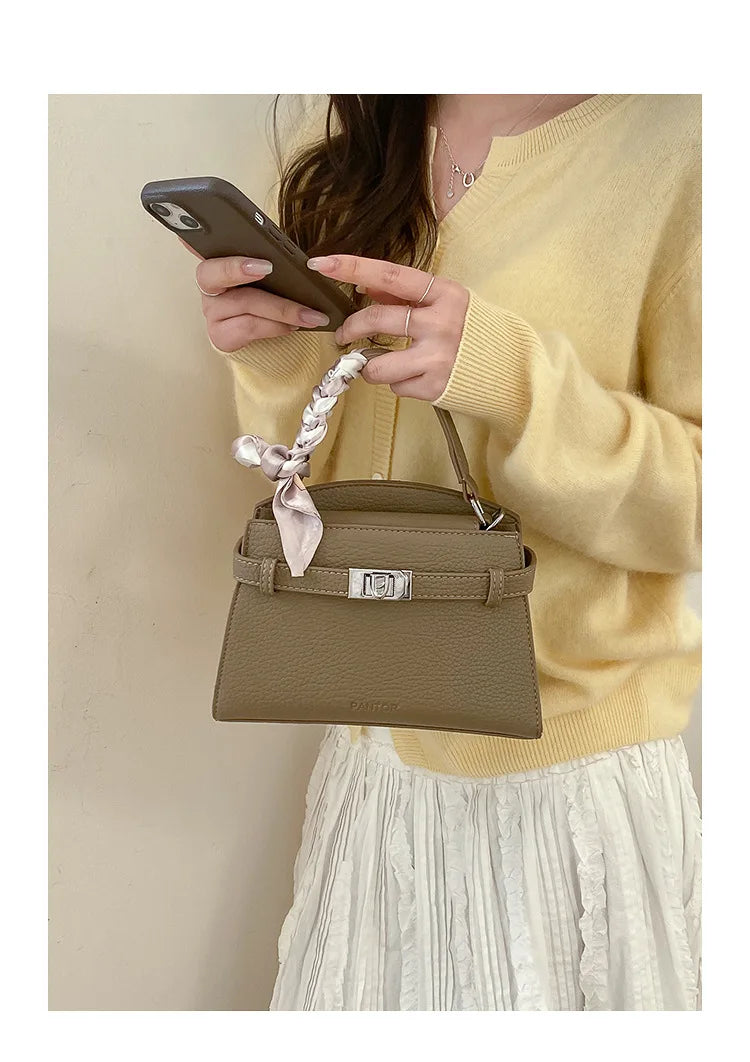 A woman holds a beige PU leather crossbody clutch bag and a smartphone against a light background.