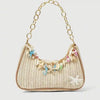 A beige woven straw shoulder bag decorated with colorful ocean charms and gold chain details.
