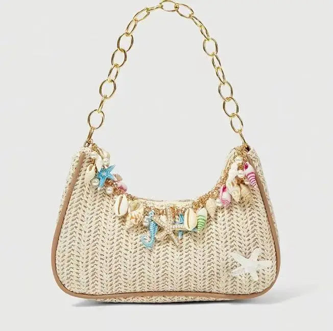 A beige woven straw shoulder bag decorated with colorful ocean charms and gold chain details.