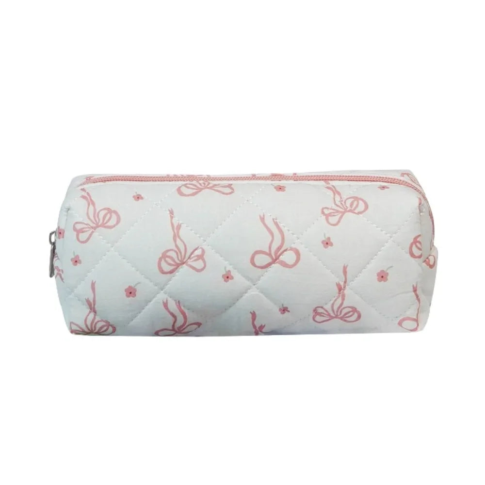 A light pink quilted cosmetic bag with a white background featuring pink floral embroidery.