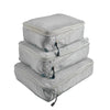 A set of three light gray reusable compression packing cubes stacked together.