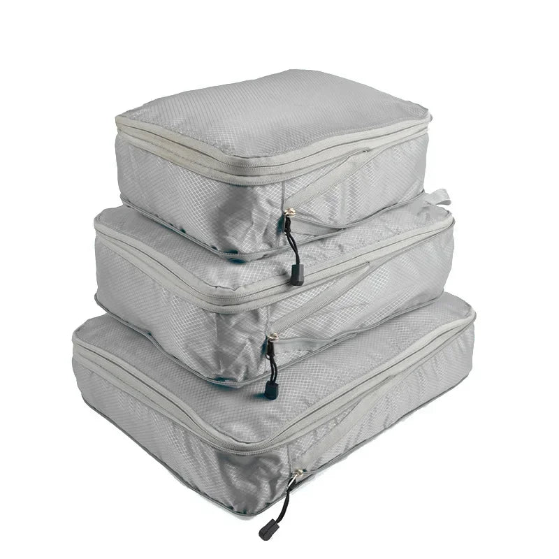 A set of three light gray reusable compression packing cubes stacked together.