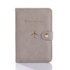 A light gray leather passport holder with a gold airplane emblem and a leather flap.