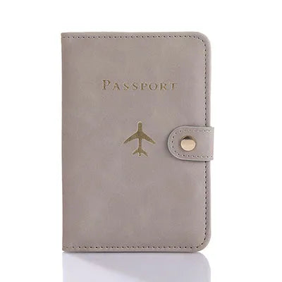 A light gray leather passport holder with a gold airplane emblem and a leather flap.