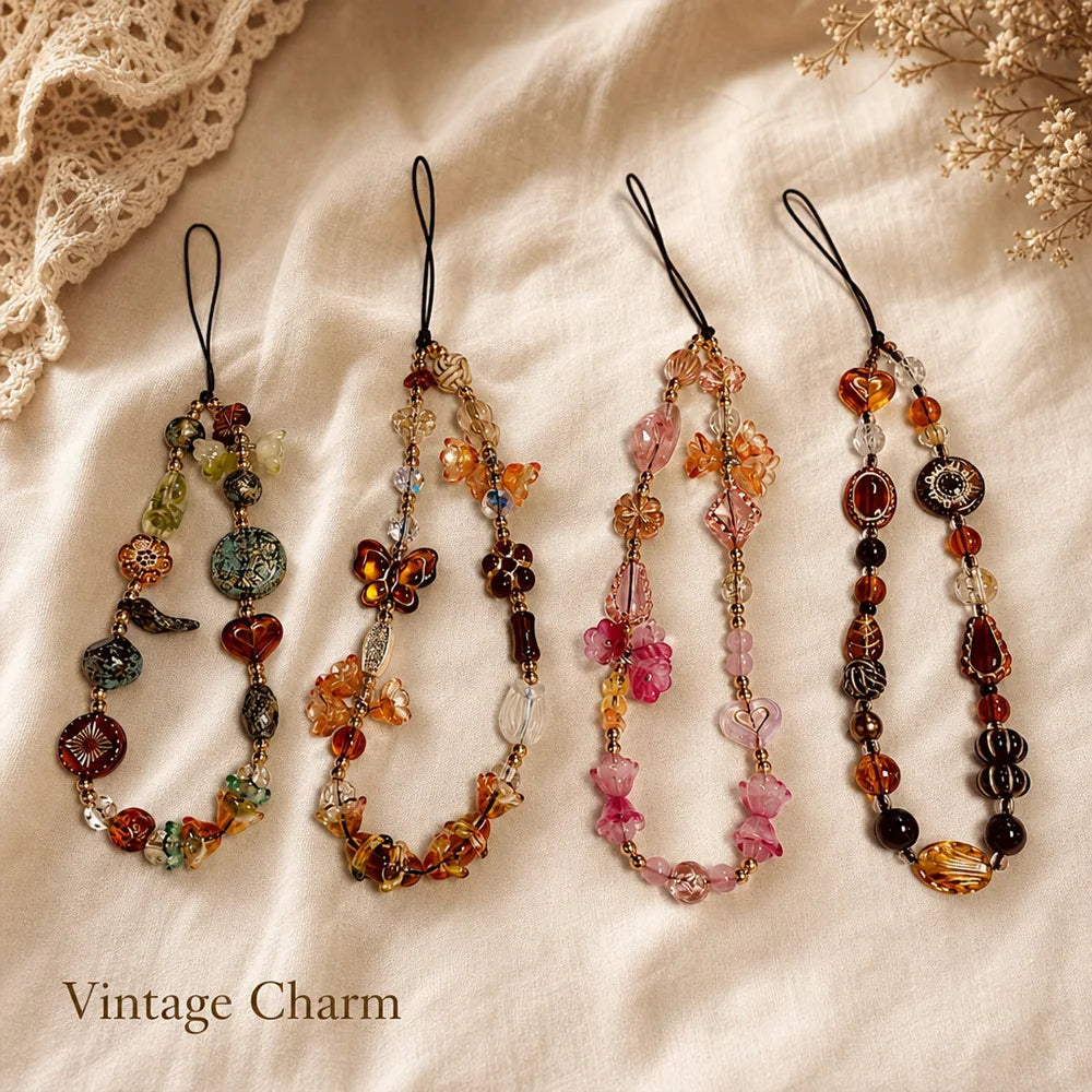 A collection of vintage beaded phone charms on a beige fabric background.