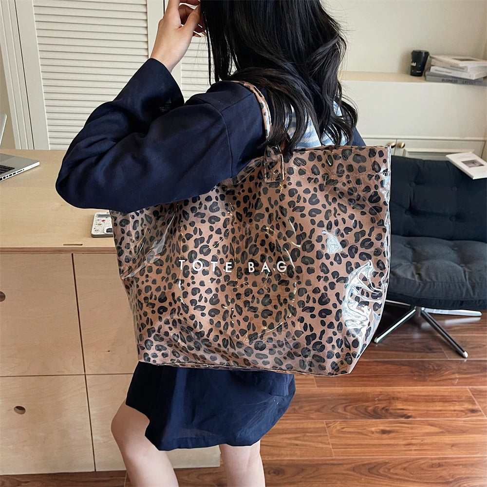 Eine Frau hält eine leopardmusterige PVC-Tasche in hellbrauner Farbe auf einem Holzschreibtisch.