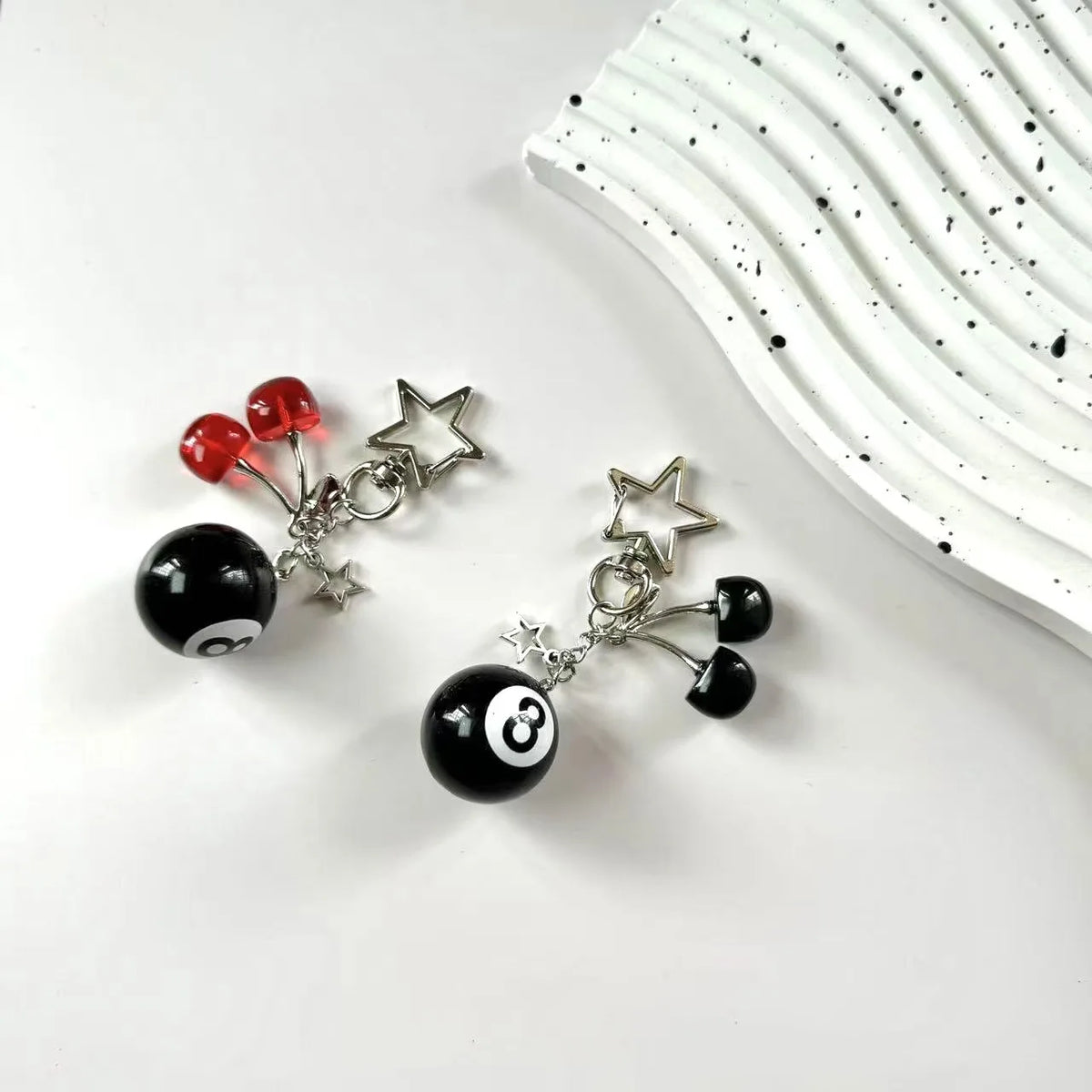 A silver and black Y2K 8 ball keychain with red accents and a star charm resting on a white background.