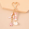 Gold-toned starfish keychain with pink and white pearl beads on a heart-shaped charm