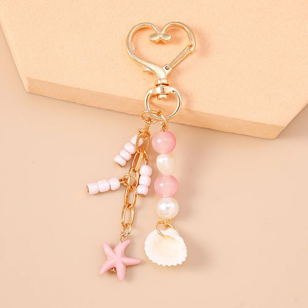 Gold-toned starfish keychain with pink and white pearl beads on a heart-shaped charm