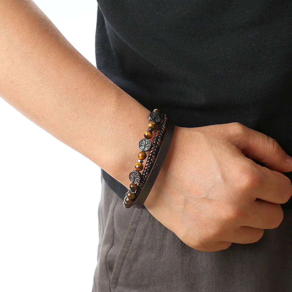 A close-up of a men's multi-layer leather bracelet featuring dark tiger eye beads worn on a wrist.