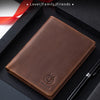 A brown genuine leather passport and travel wallet resting on a black box with a pen.
