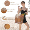 A woman holds a woven mesh beach tote bag with woven shoulder straps on a sandy beach.