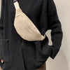 A dark gray knitted cardigan with a beige nylon crossbody sling bag worn across the chest.