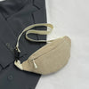 A light beige nylon crossbody sling bag is shown resting on a dark gray blazer.