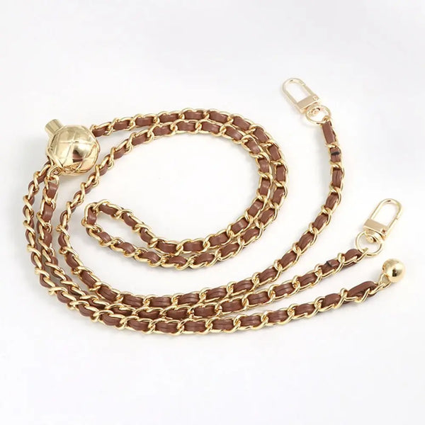 A close-up of a brown leather adjustable metal shoulder strap bracelet with gold-toned hardware.