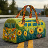 A vintage sunflower quilted duffle bag with green fabric and orange handles resting on asphalt.
