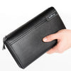 A black leather business handbag clip wallet is held by a hand, showing the texture and branding.