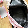 Sac à dos rose et blanc à motif de chat, ouvert, montrant l'intérieur noir.