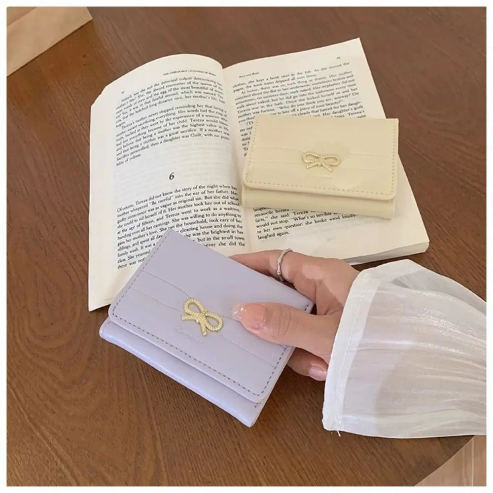 Une main tient un porte-cartes pliable violet clair à deux volets à côté d'un carnet ouvert.