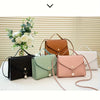 A collection of five beaded square crossbody bags in shades of brown, green, pink, and beige displayed on a white surface.