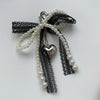 A pearl bowknot keychain featuring black lace and a silver heart charm.