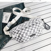 A plaid checkered crossbody chest bag in gray and white with a white adjustable strap resting on a wooden surface.