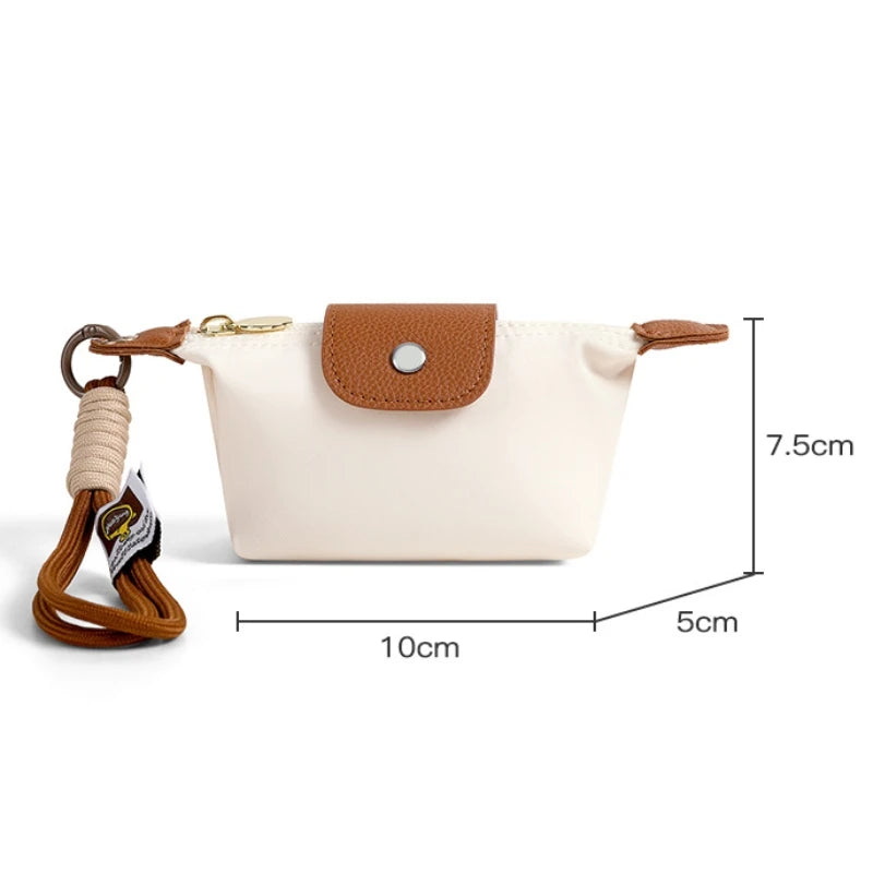 Beige faltbare Geldbörse mit braunem Lederverschluss und Armband, von der Seite gezeigt.