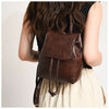 Une femme vue de dos portant un mini sac à dos en cuir marron avec un haut de tissu clair.