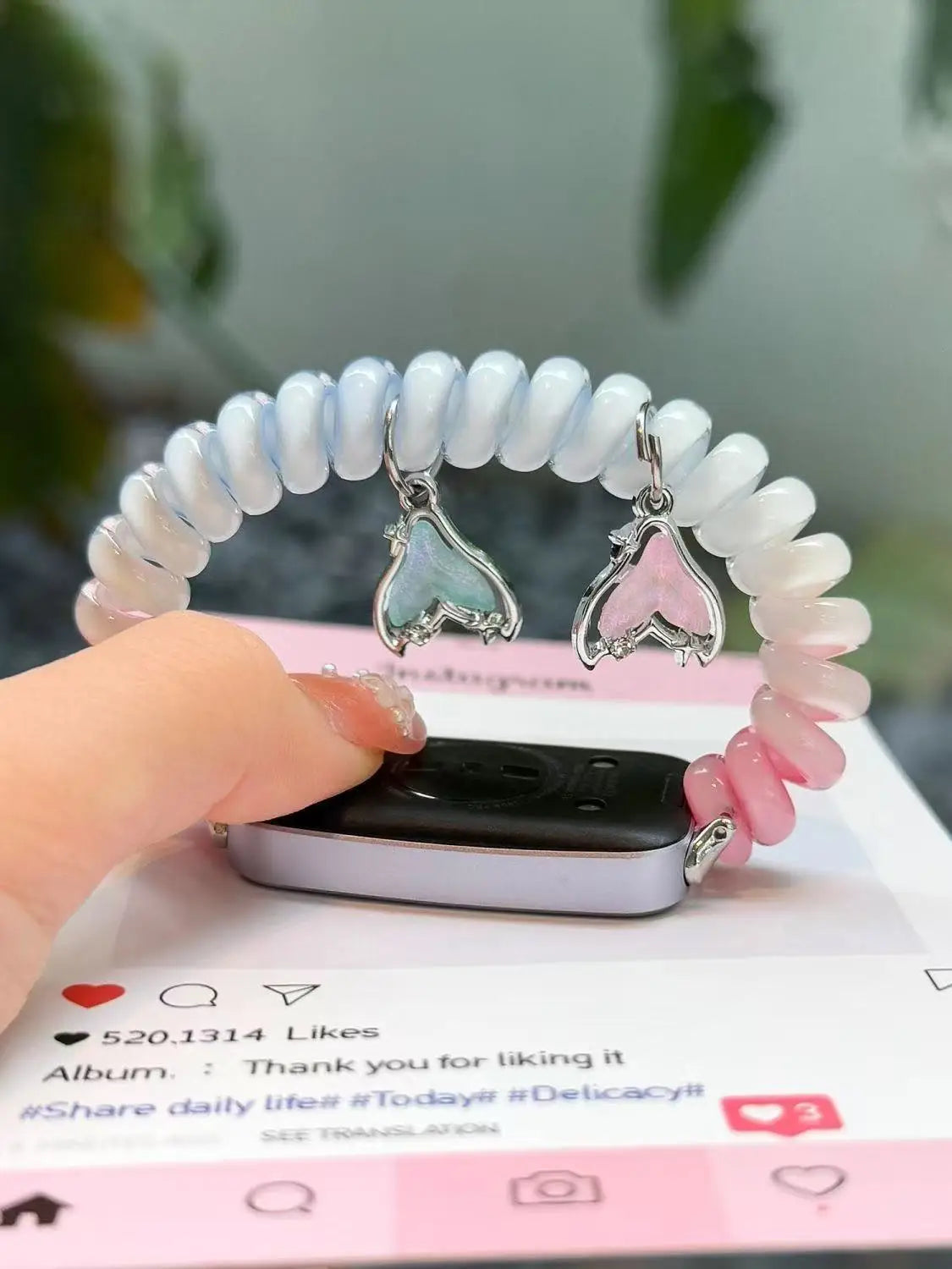 A hand holds a white and pink elastic watch strap for a Huawei band next to a smartphone.